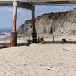 Photo of workers on the beach around a steel pile support